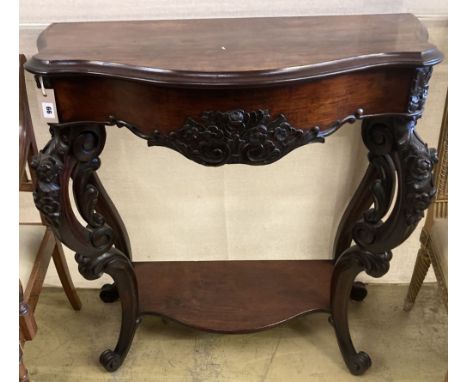 A Victorian carved walnut serpentine front two tier console table with hinged top, width 98cm, depth 41cm, height 94cm
