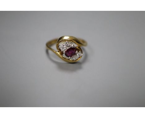 A modern 18ct gold, single stone ruby and four stone diamond set crossover ring, size L, gross 3.5 grams.CONDITION: Small nic