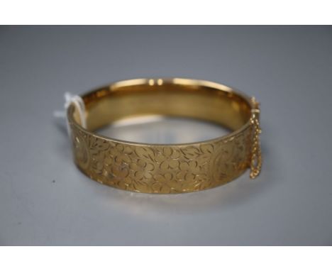 A modern engraved 9ct gold hinged bangle, gross 26.8 grams.