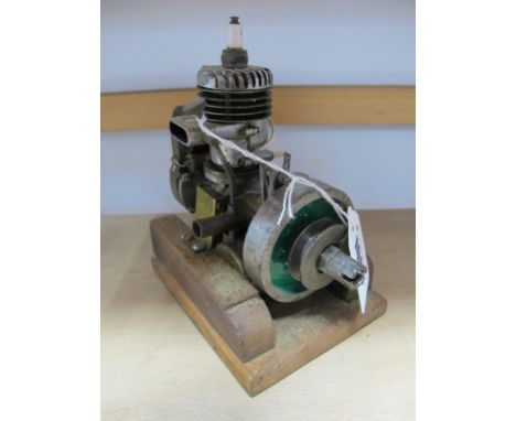 A Model Two Stroke Petrol Engine, fitted with fuel tank, generator and two inch flywheel, mounted on a wooden base with an ov