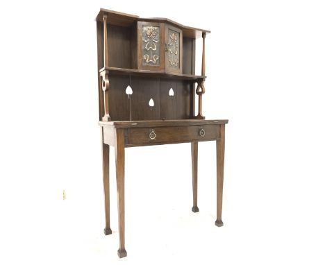 Early 20th century oak Arts and Crafts writing desk, raised back with open shelf and cupboard to centre with hammered brass p