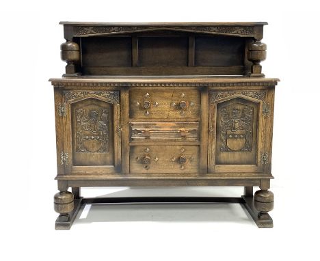 Early 20th century medium oak sideboard, raised back with floral carved frieze, two cupboards under each enclosing fixed shel