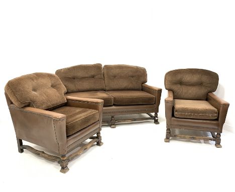 Early 20th century three piece suite, comprising a two seat sofa upholstered in studded leather with squab cushions, raised o