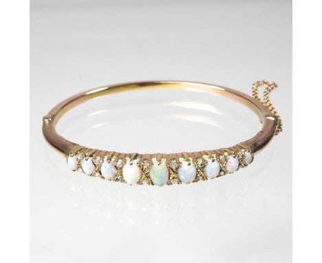 An unmarked opal hinged bangle, set with a single row of nine graduated opals, separated by diamonds, with a hinged clasp and