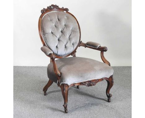 A Victorian carved walnut and green upholstered button back armchair, on cabriole legs