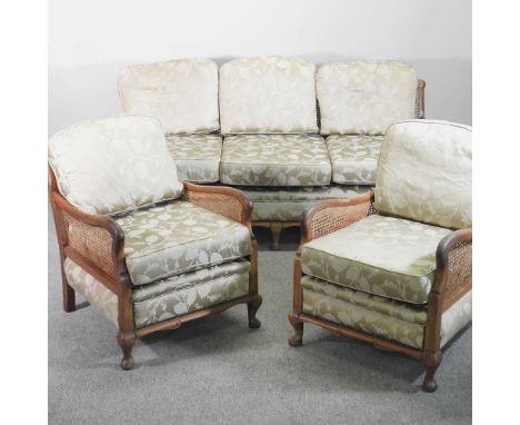 A 1920's walnut single cane bergere suite, with green floral cushions, comprising a sofa and pair of armchairs (3)180w x 80d 