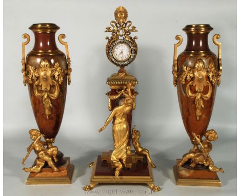 An exceptionally elegant French, Rosso Rubino Marble and Ormolu Clock and Garniture.  The enamel clock face surrounded by pas