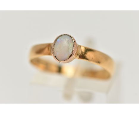 AN OPAL YELLOW METAL SINGLE STONE RING, set with an oval opal cabochon, within a milgrain setting, to the plain polished band