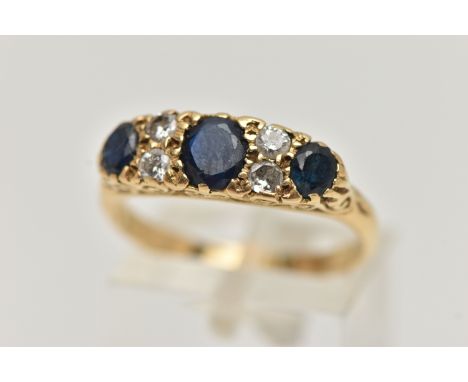 A YELLOW METAL SAPPHIRE AND DIAMOND RING, set with three oval cut deep blue sapphires, interspaced with four round brilliant 