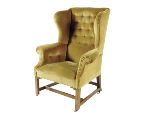 A wing armchair, with button upholstered dralon on mahogany supports united by an 'H' stretcher and on ceramic castors.