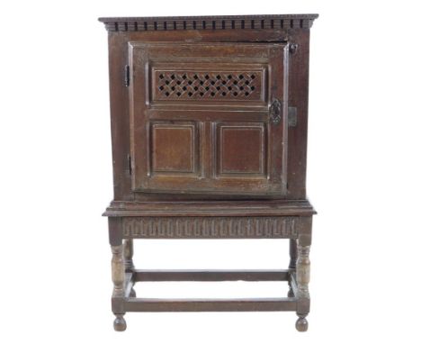 A late 17th century oak food cupboard, the cornice with incised decoration above a fielded panel door with an open lattice ve