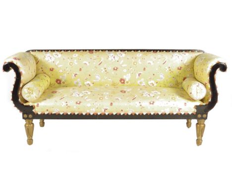 A William IV ebonized scroll end sofa, on lappet carved gilt legs and brass roller castors, 90.7cm high, 215cm wide, 67cm dee