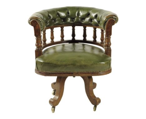 A late Victorian oak desk chair, with a swivel seat and with button upholstered green leather.