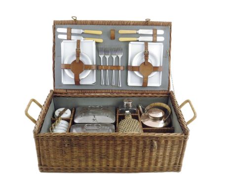 A wicker tea for four picnic basket, fitted with enamel plates and cups, cutlery, a ceramic butter pot and cover, glass jars,