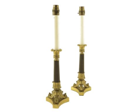 A pair of Louis Philippe ormolu and patinated candlesticks, with a lappet and ribbed stem on tripod scroll feet, later conver