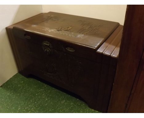 20th century camphor wood storage trunk with decorative carved Oriental scenes to front and top panel, stepped sides, 40ins x