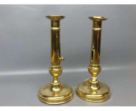 Pair of brass candlestick, with slide ejector to column, raised on a circular base, height 9 ins tall 
