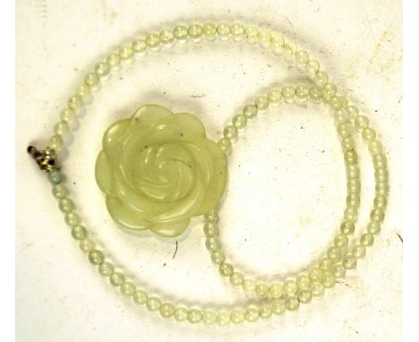 A contemporary carved white jade pendant, in the form of a flower, attached to a matching bead necklace, 24cm long when undon