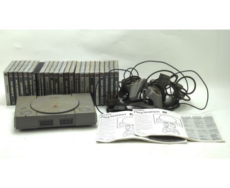 A Playstation One console with two related controllers and a selection of games, including Worms, Driver and Asteroid.
