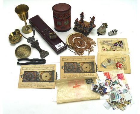 An assortment of collectables, including a brass goblet, embroidered postcards, a papier mache money box, a nutcracker, two d