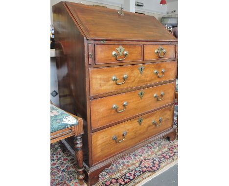 A George III mahogany bureau, of cleated form enclosing a fitted interior above two short and three long drawers on shaped br