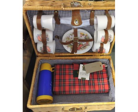 A picnic hamper, the wicker basket fitted with blanket, thermos flask and ceramics for four place settings.