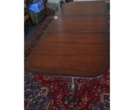A George III style twin pedestal dining table, the top with a reeded edge on turned supports and tripod bases with moulded sa