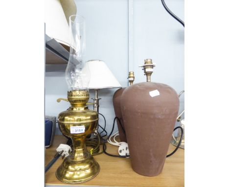 A BRASS OIL LAMP, TWO BROWN POTTERY TABLE LAMPS AND SHADES AND ANOTHER 