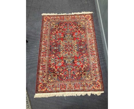 A red ground Persian rug, late 20th century, with a complex knot motif to the central panel, 224 x 146cm