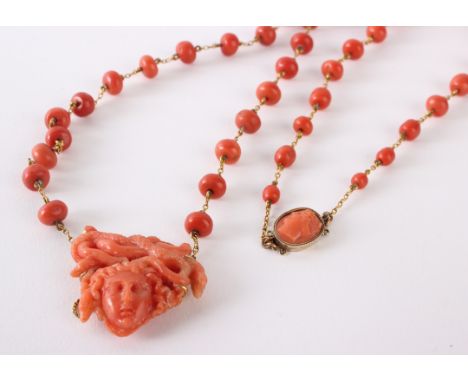 A pink jade/coral necklace on gold coloured chain with a Medusa head pendant