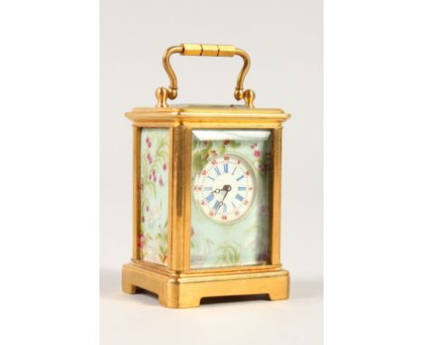 A MINIATURE CARRIAGE CLOCK, with brass case and decorative porcelain panels. 5.5cms high.
