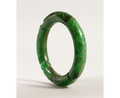 A CHINESE GREEN JADE BANGLE, with carved decoration. 8.5cms diameter.