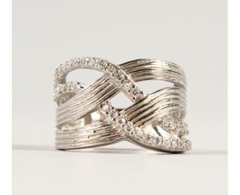 A SILVER AND CZ CROSSOVER RING.