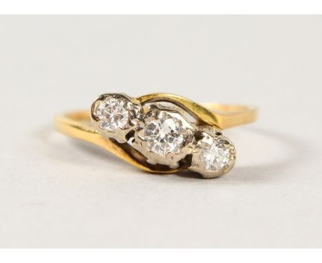 AN 18CT GOLD THREE STONE DIAMOND CROSSOVER RING.