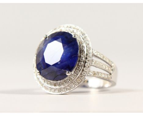 A 14K WHITE GOLD AND DIAMOND RING, set with an oval cut blue sapphire approx. 6.50ct, diamonds approx. 1.10ct total weight.