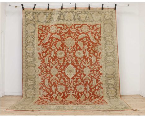 A hand knotted Agra carpet, the red fields with all over scrolling foliate decoration within a turquoise flowerhead decorated