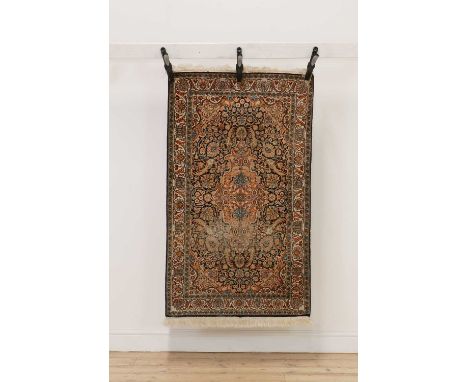 A hand knotted silk Persian rug, the rose and biscuit fields with allover foliate decoration in a triple border,136 x 75cmCon