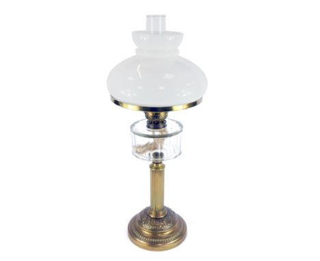 An early 20thC brass oil lamp, with a shaped white glass shade and funnel, with glass reservoir on a brass fluted stem, with 