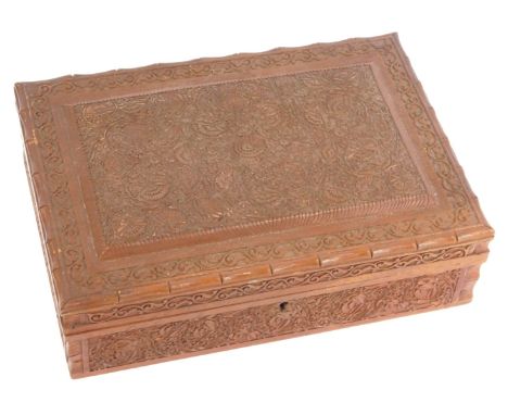 An early 20thC Anglo Indian wooden cigarette box, profusely carved with scrolling flowers and leaves, the hinged lid opening 