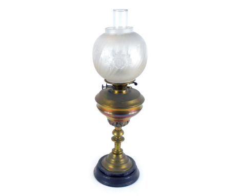 An early 20thC brass oil lamp, with a circular frosted shade, with etched floral decoration, with chimney, on a brass leaf ca