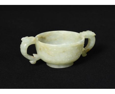 A small jade twin handled cup, 19th century, of compressed globular form and raised on a low foot, with two handles, each for