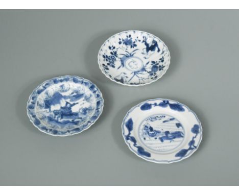 Three Kangxi period small dishes, one painted with two horse-borne figures within three sprays of pine on a barbed rim, 11cm 