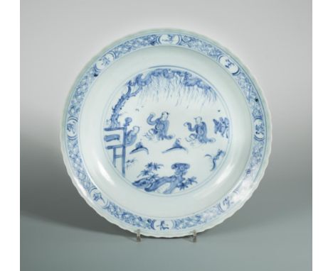 A Ming dynasty celadon charger, painted with three figures under a willow tree, the flute-incised back under a celadon base, 