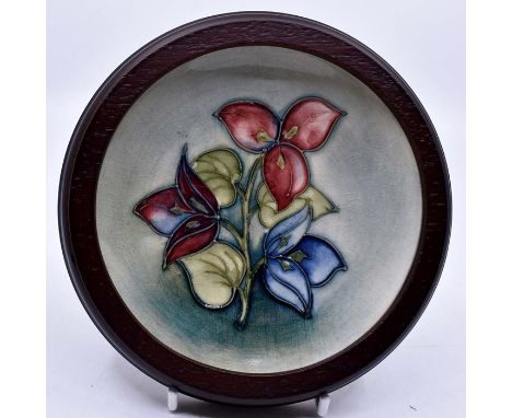 Moorcroft: A Walter Moorcroft 'Bougainvillea' pattern coaster on a light green wash ground in a wooden frame. Diameter 11.5cm