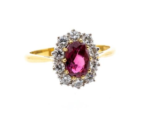 A ruby and diamond 18ct gold cluster ring, oval claw set ruby to the centre approx 7 x 5mm, within a border of brilliant cut 