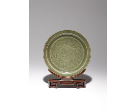A CHINESE LONGQUAN CELADON 'LOTUS' DISH MING DYNASTY The shallow body rising to a flat everted rim, carved with a central flo