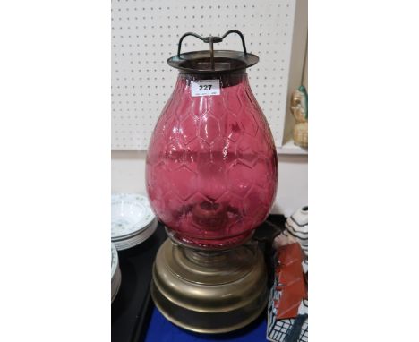 A large church oil/heater lamp with squat brass base fount and a cranberry glass shade in a honeycomb pattern one handle has 