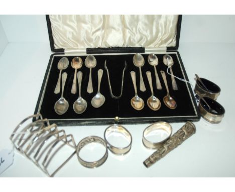 A lot comprising a cased set of EP coffee spoons &amp; tongs with a silver toast rack, Sheffield 1925, three silver napkin ri
