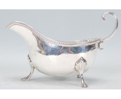 An early 20th century Edwardian Charles and George Asprey silver gravy boat raised on claw feet with gadrooned rim and scroll