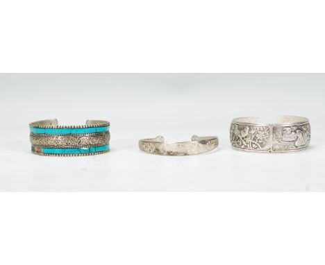 A group of three Chinese white metal bangles / bracelets to include a bangle decorated in relief with birds of paradise, deer